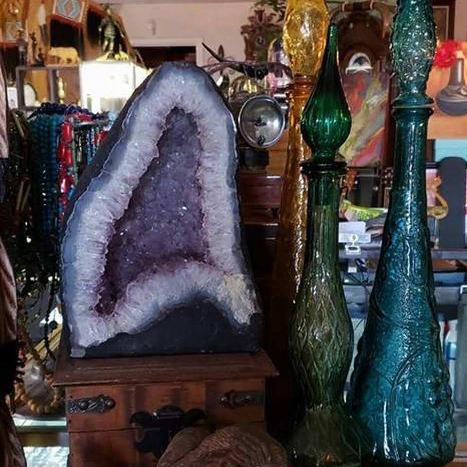 Large amethyst geode beside green glass bottles